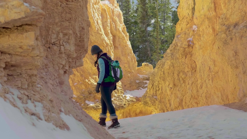 Girl woman hiking with red rocks formation and snow near Bryce Canyon in southern Utah.