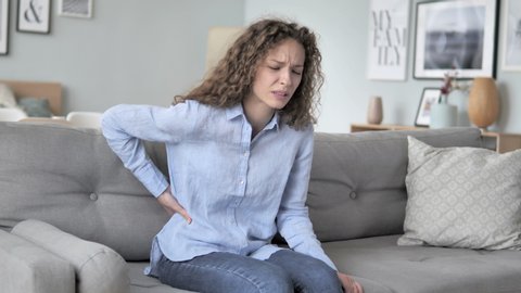 Curly Hair Woman with Spinal Back Pain Sitting on Couch