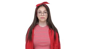 Pretty unhappy young girl in red shirt making thumbs down gesture and showing tongue while looking at the camera over white background isolated