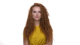 Upset young redhead curly lady shaking head and touching her face because of worrying about something while looking at the camera over white background isolated