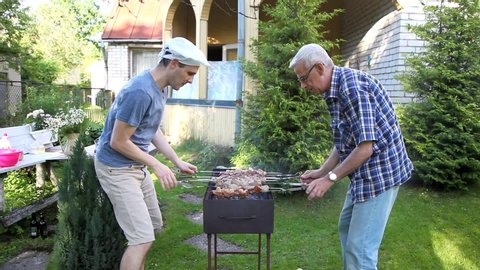 Funny video: frying meat like playing table hockey.  Two men are frying shish kebab, freaking and joking.