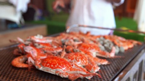 Close-up grill crab prawn and shell on flaming Charcoal stove. Group of tourist having BBQ, Seafood party at seaside.
