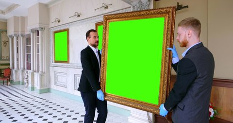 Scientific officers of art gallery hanging picture on wall. Green screen, slow motion, chromakey