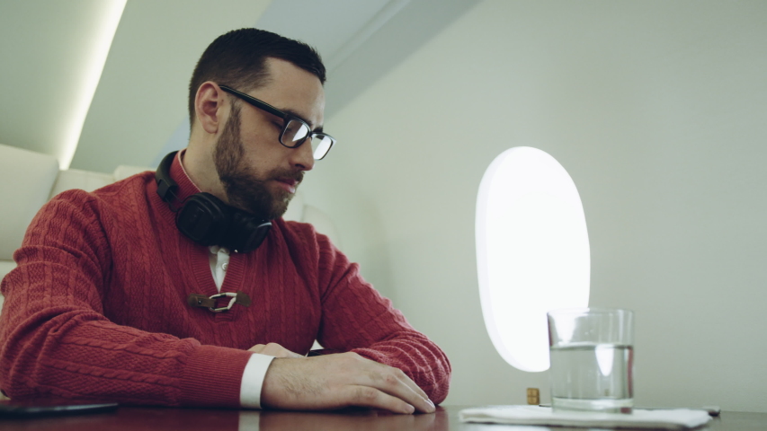 Close-up. portrait of a handsome upset business man who drinking water at the airplane during the flight. Slow motion. 