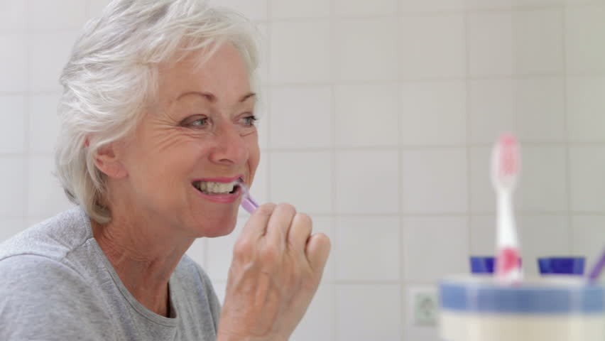 Senior woman brushes teeth in bathroom mirror pausing to check they are clean. Shot on Canon 5d Mk2 with a frame rate of 30fps Royalty-Free Stock Footage #10319468