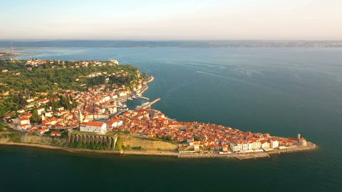 4K. Flight over old city Piran at golden sunset, aerial panoramic view with old houses, Tartini Square, St. George's Parish Church, fortress and marina.