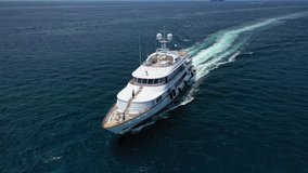 Aerial drone video of luxury yacht cruising deep blue open ocean sea