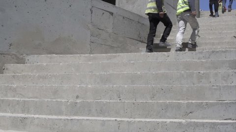 Low angle view of construction workers exit stairs - slow motion