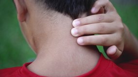 Back of a kid's neck as he rubs it because of pain