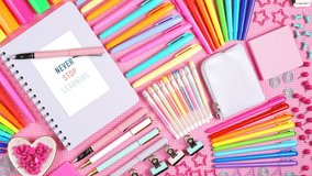 Back to school or workspace colorful stationery overhead on pink background flat lay slow panning.