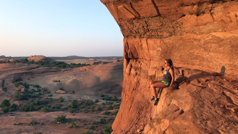 Woman resting on rock from free climbing in desert of Utah at sunset