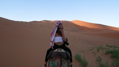 Women riding a Camel, looking back and smiling towards the Camera.