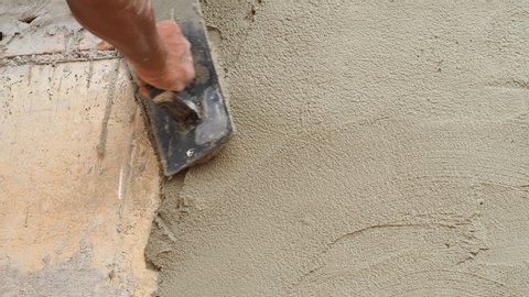 builder worker or plasterer hands use trowel to plastering on cement wall by manual work. keep detail construction before finishing works. construction and industry concept. motion 4k b-roll footage