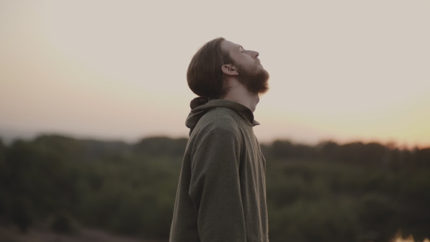 Bearded guy Caucasian appearance,stands in nature and meditates, kneads his neck