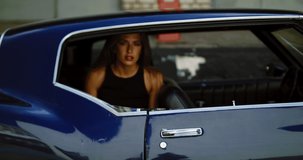 Beautiful Caucasian female posing with an old classic retro muscle car. Automotive lifestyle. 4K UHD RAW graded footage
