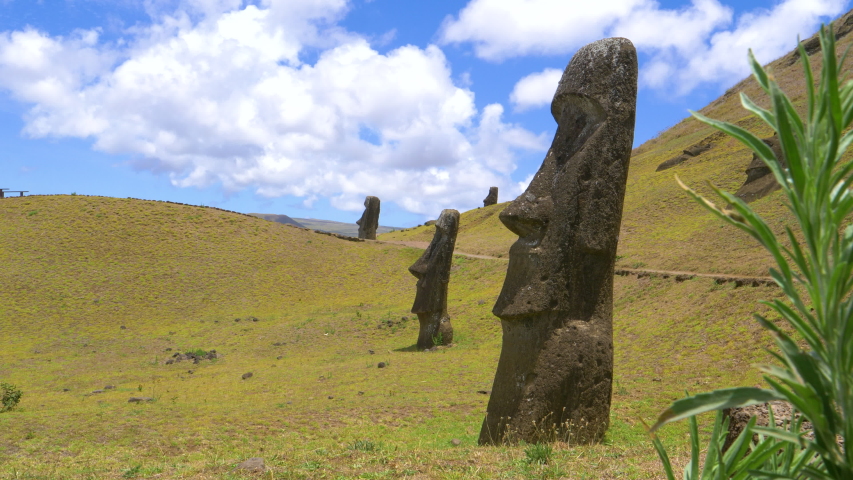 CLOSE UP: Scenic view of the green landscape and breathtaking volcanic sculptures scattered around the picturesque Easter Island. Empty path runs across the meadows close to a volcanic quarry in Chile