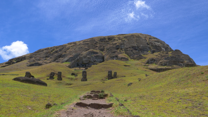 DRONE: Mysterious moai statues face empty trail leading up to the volcano on Easter Island. Breathtaking drone view of the volcanic landscape and ancient sculptures on remote exotic island in Chile.
