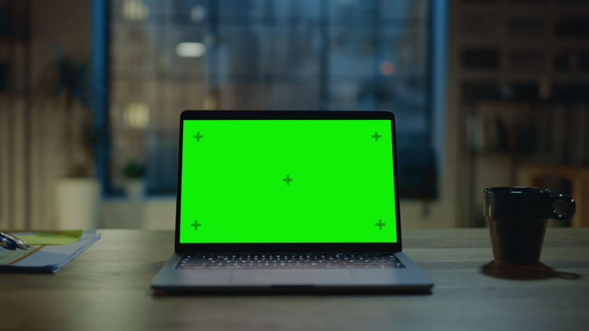 Mock-up Green Screen Laptop Standing on the Desk in the Modern Creative Office. In the Background Warm Evening Lighting and Open Space Studio with City Window View. Zoom out Shot Royalty-Free Stock Footage #1031975654