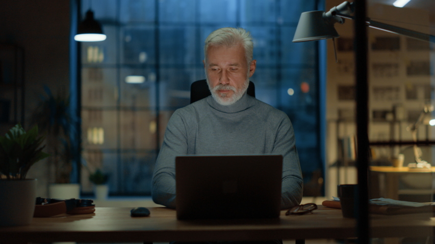 Portrait of the Handsome and Successful Middle Aged Bearded Businessman Working at His Desk Using Laptop Computer, Checks His Smartphone. Working from Cozy Home Office / Studio. | Shutterstock HD Video #1031975774