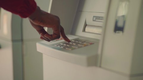 Close up of Afro-American businessman entering his pin code on keyboard of ATM, banking service, finance and people concept. Transfer, cash withdrawal. Soft selective focus