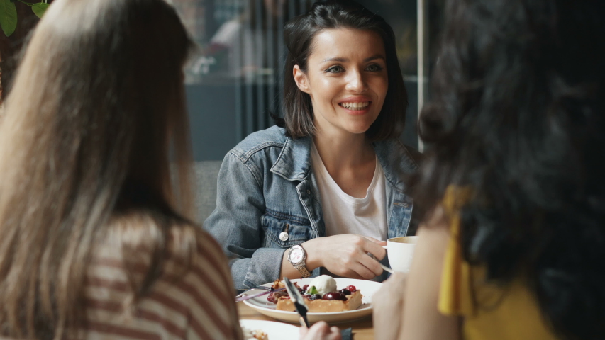 Young women are eating desserts and drinking coffee in cafe talking having fun enjoying leisure time and meeting with friends. People and happiness concept. Royalty-Free Stock Footage #1031981834