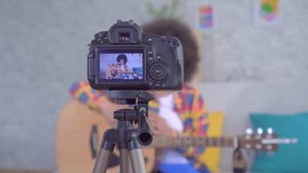 African woman blogger with an afro hairstyle with a guitar the view through the camera screen
