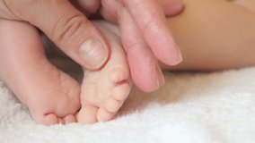 mother gently touches the fingers of her baby, motherhood