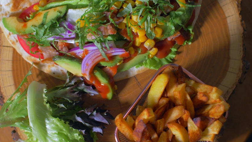 Delicious mexican food burrito and fried potatoes served on a wooden board