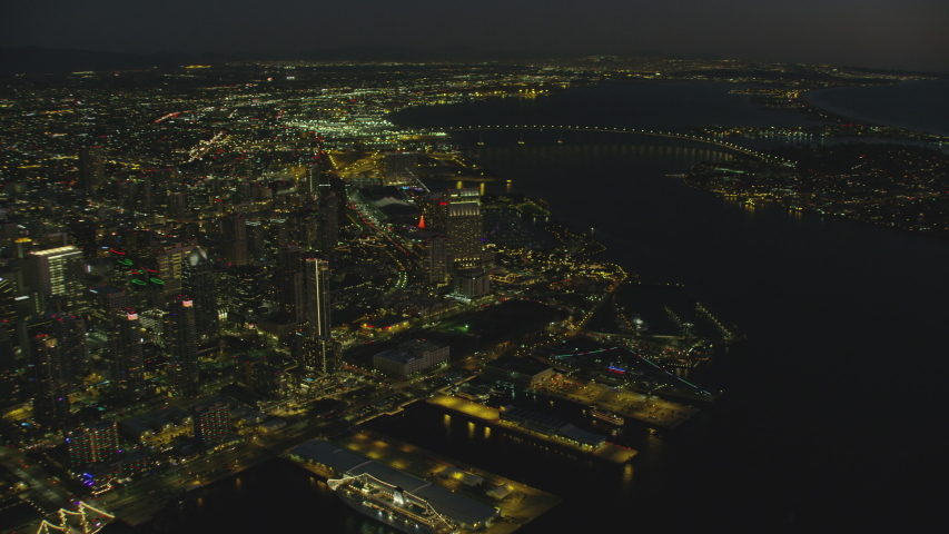 Aerial night illuminated view of San Diego bay Downtown city skyscrapers International Cruise ship Terminal USS Midway museum Coronado vehicle bridge California USA RED WEAPON