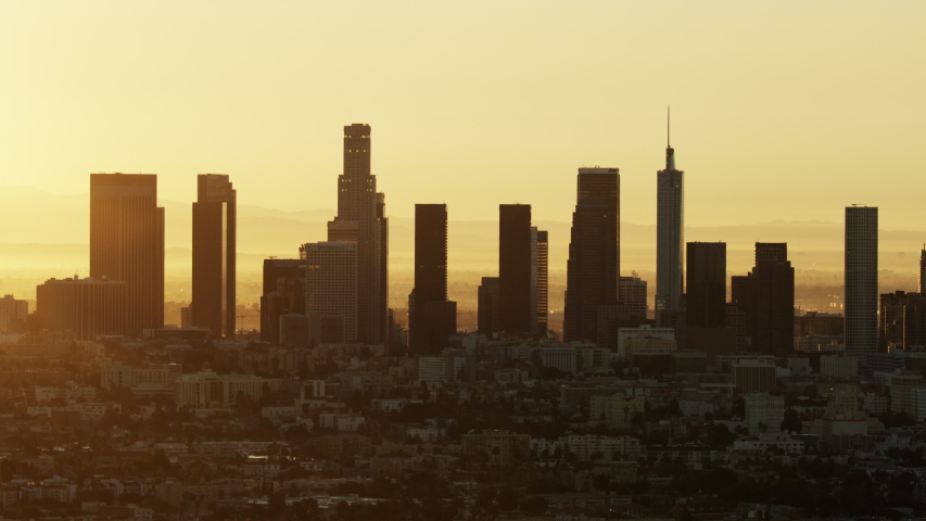 Aerial sunrise view across urban neighborhood commercial and residential buildings with city skyscrapers Los Angeles skyline California USA | Shutterstock HD Video #1032005804