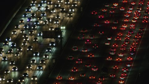 Aerial sunset view Los Angeles multi lane freeway traffic congestion with vehicle headlights and brake lights California USA