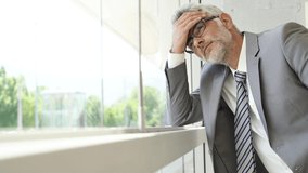 Tired businessman leaning on window