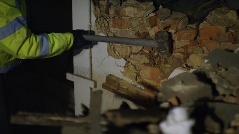 Labourer using a sledgehammer to knock down a wall, in slow motion