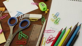 School stationery: multi-colored pencils, paper clips, ruler, pencil sharpener, magnifier, smiles blue and green binder clips on notebook. Concept of back to school and education