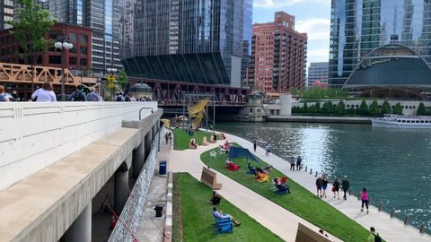 Chicago, IL / USA - 6/13/19: Chicago's upper and lower city, with view of Upper Wacker and the riverwalk below. Contrasting view where commuters hurry and tourists find leisure.