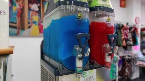 Pan shot of red and blue slushy machines, blending liquids
