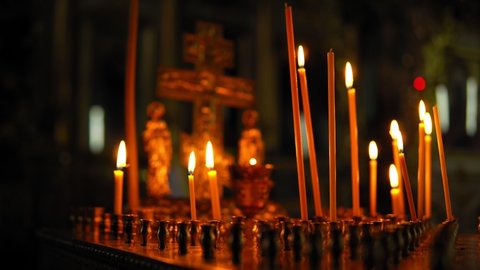 Russian Orthodox Church, traditions and rites. Candlestick with burning candles for the repose and cross of gold colors with small figurines in the temple in the Church.