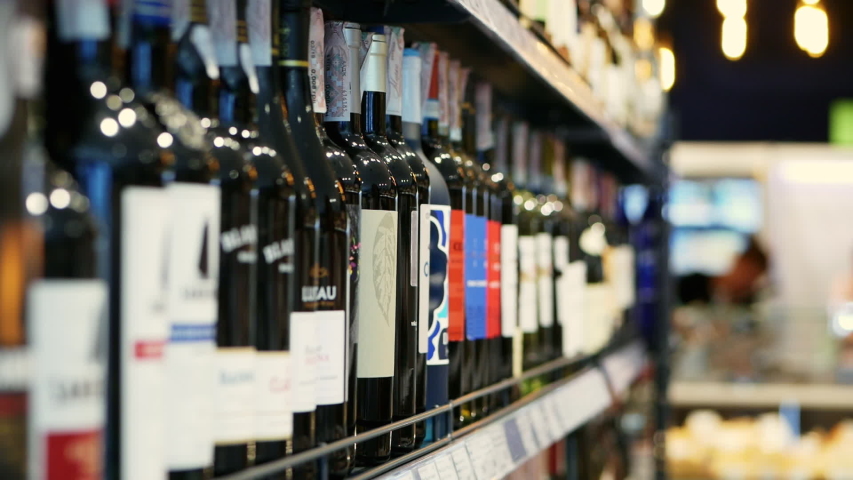 Woman chooses wine in the Supermarket, customer selects product on the shelves in the store in close-up Alcohol sale Royalty-Free Stock Footage #1032081818