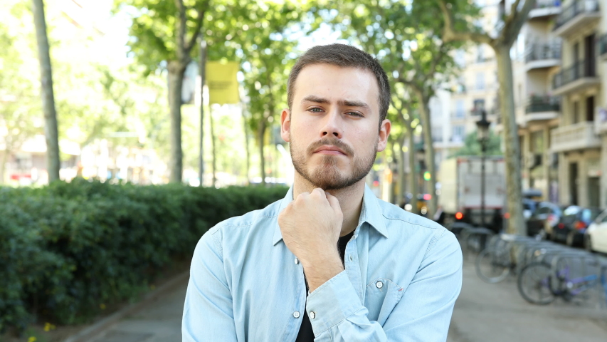 Front view of a suspicious man listening to you doubting in the street Royalty-Free Stock Footage #1032083021