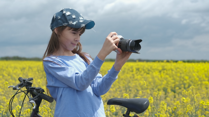 Young girl photographer. Girl teenager with a camera on a rapeseed field.