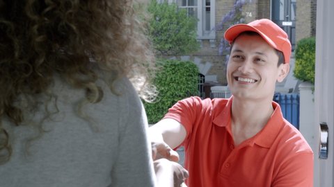 A woman opens her front door to a smiling delivery man delivering delicious takeaway food. Online ordering and delivery concept.
