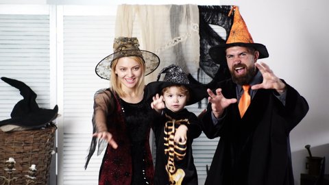 Happy family mother father and child boy in costumes and decoration on a celebration of Halloween. Happy family in costumes getting ready for halloween at home. Halloween background. Halloween party