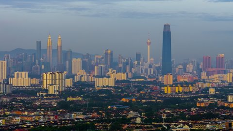 Time lapse: Kuala Lumpur City view during dawn overlooking the city skyline from afar as the first light hits the landscape at sunrise from night to day in Malaysia.