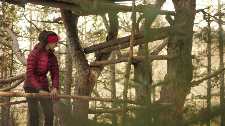 Woman Testing The Structure Integrity Of A Treehouse In The Woods.