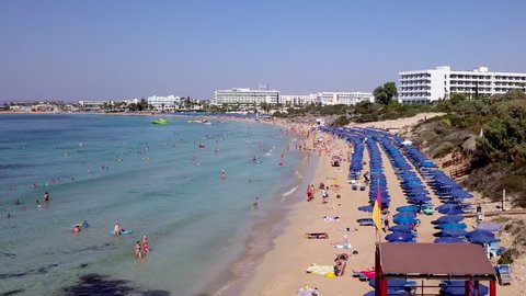 Aerial view of a holiday resort sandy beach, with beach umbrellas and sun beds. Crowded sandy beach in Ayia Napa Cyprus.