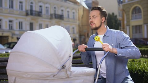 Father swinging newborn carriage feeling tired, infant care difficulties, colic