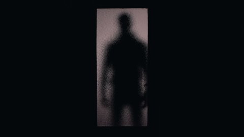 Silhouette of robber or maniac standing behind glass door, phobias and fears