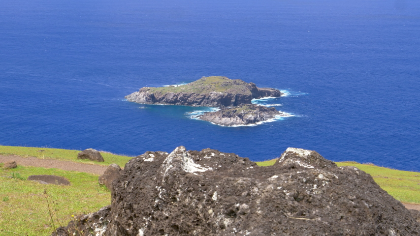 CLOSE UP: Scenic view from above of small rocky islands near Easter Island. Picturesque view of an islet that was used for ancient bird man rituals. Islet of Motu Nui is surrounded by deep blue ocean.
