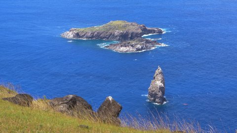 CLOSE UP: Small untouched islet of Motu Nui is surrounded by the vivid blue ocean. Spectacular view of rocky islands near Easter Island. Scenic view of an islet that was used for ancient rituals.
