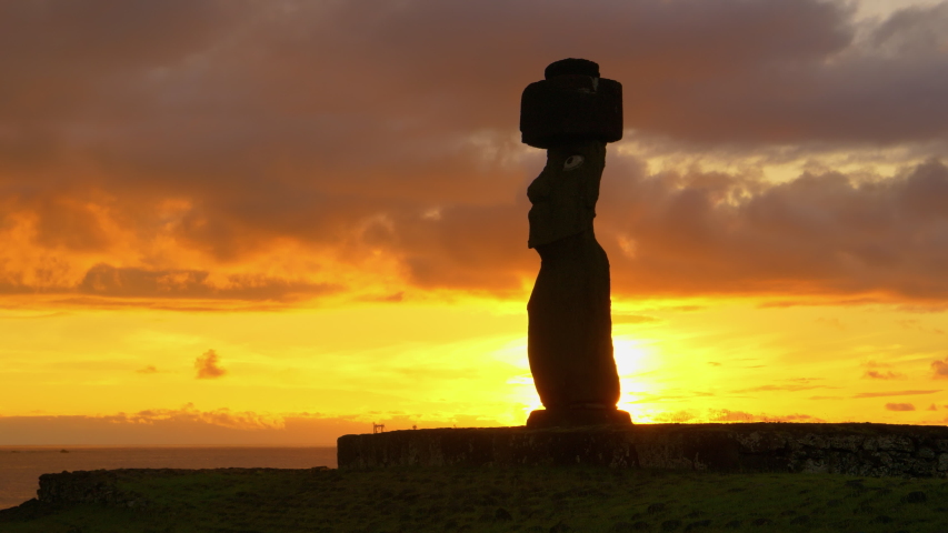 SILHOUETTE, LENS FLARE, COPY SPACE: Dark clouds gather above the historic moai statue by the scenic shore of Easter Island. Idyllic shot of sunset illuminating the ocean behind the fascinating moai